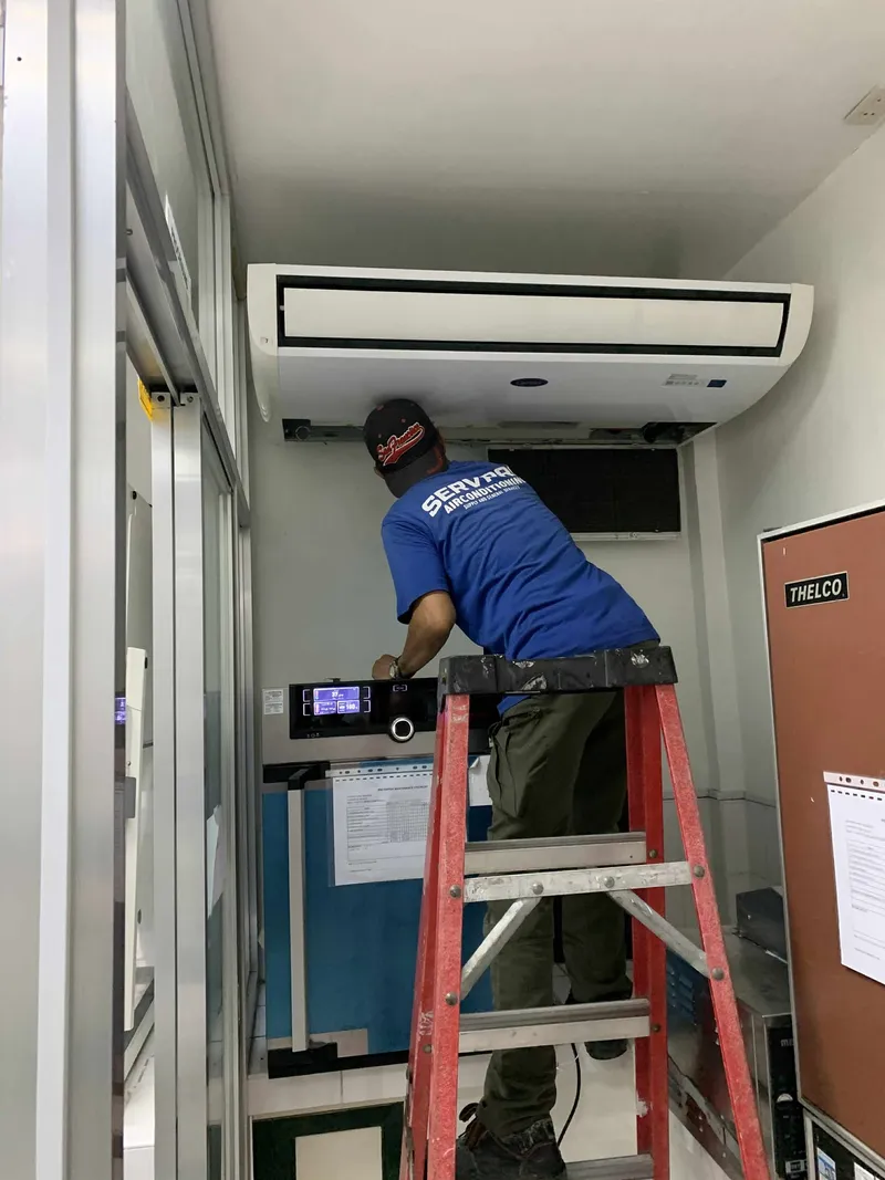 Technician servicing ceiling-mount unit