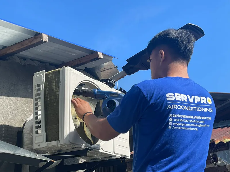 Technician cleaning outdoor condenser unit