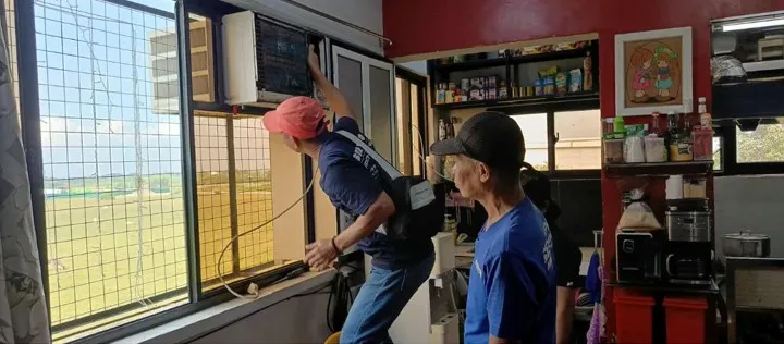 Technicians installing window type aircon unit